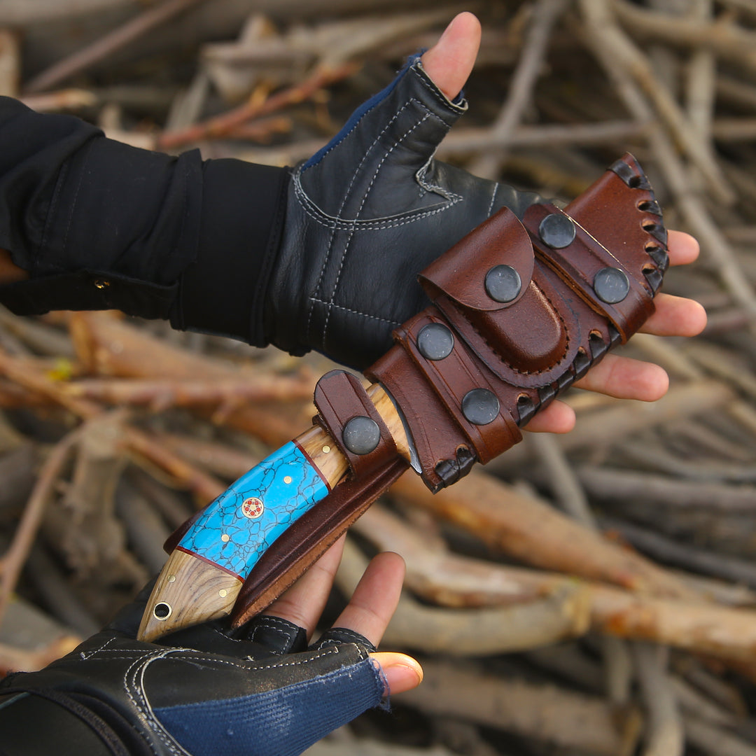 Hand holding a knife with a leather sheath against a natural background