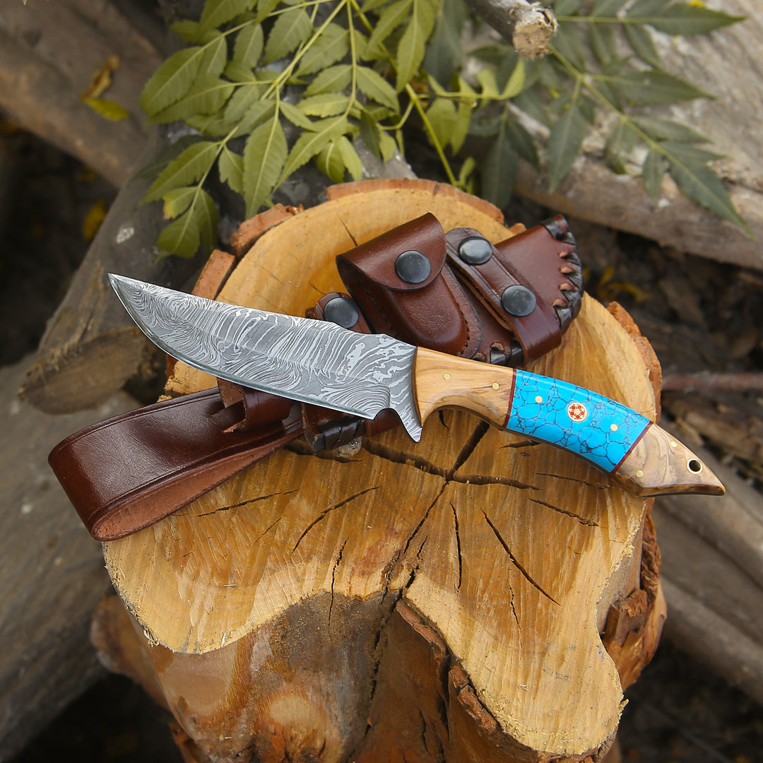 Knife with a blue handle on a wooden log with a leather sheath.