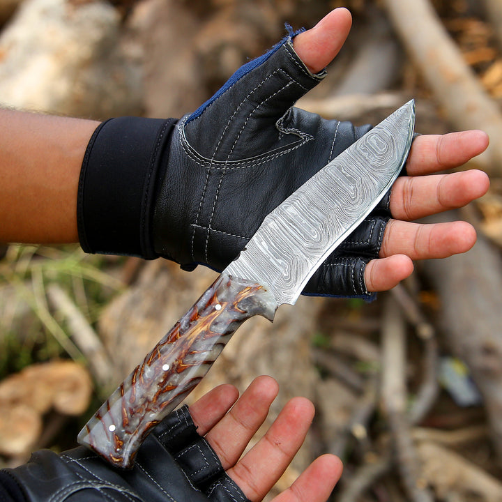 Hand holding a Damascus knife with a blurred natural background