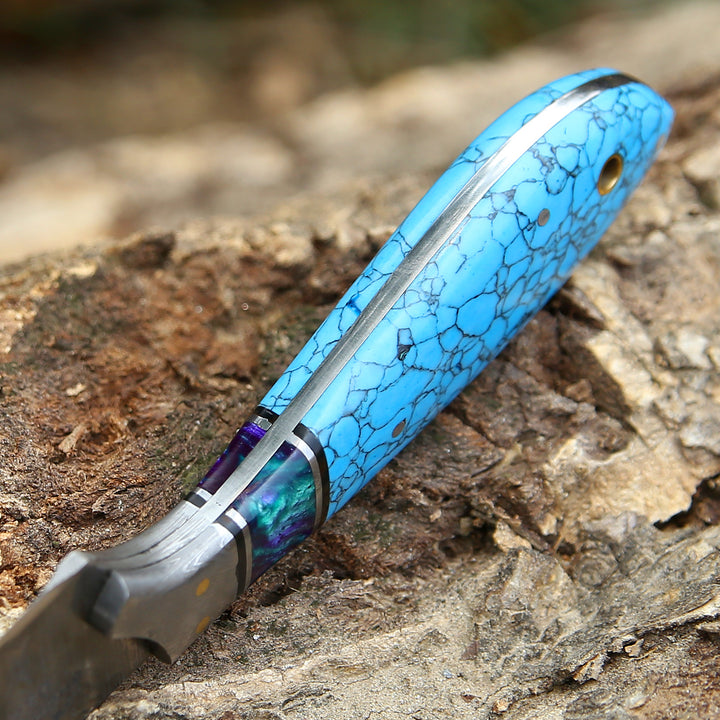 Folding knife with a blue and purple handle on a wooden surface