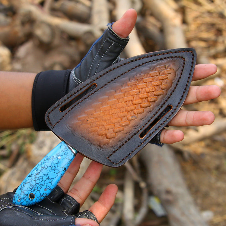Person holding a knife with a textured brown blade and blue handle against a natural background.