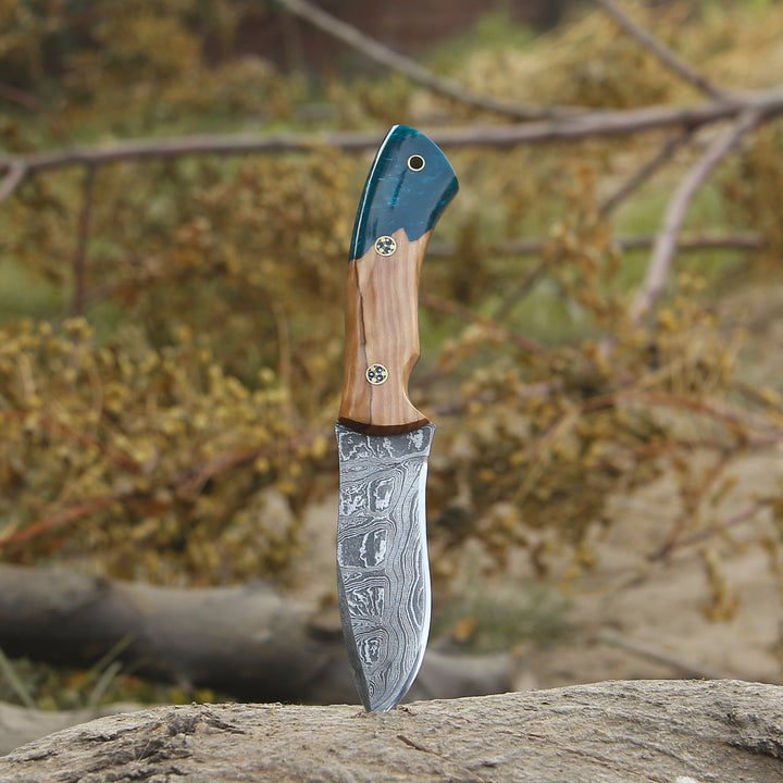 Decorative knife with a wooden handle and blue blade on a rock with a natural background