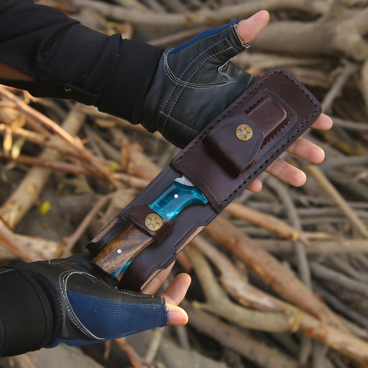 Hand holding a leather knife sheath with a blurred natural background