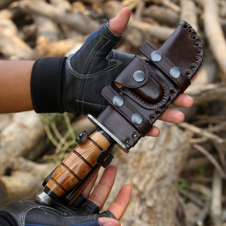Hand holding a knife with a wooden handle and leather sheath against a natural background.